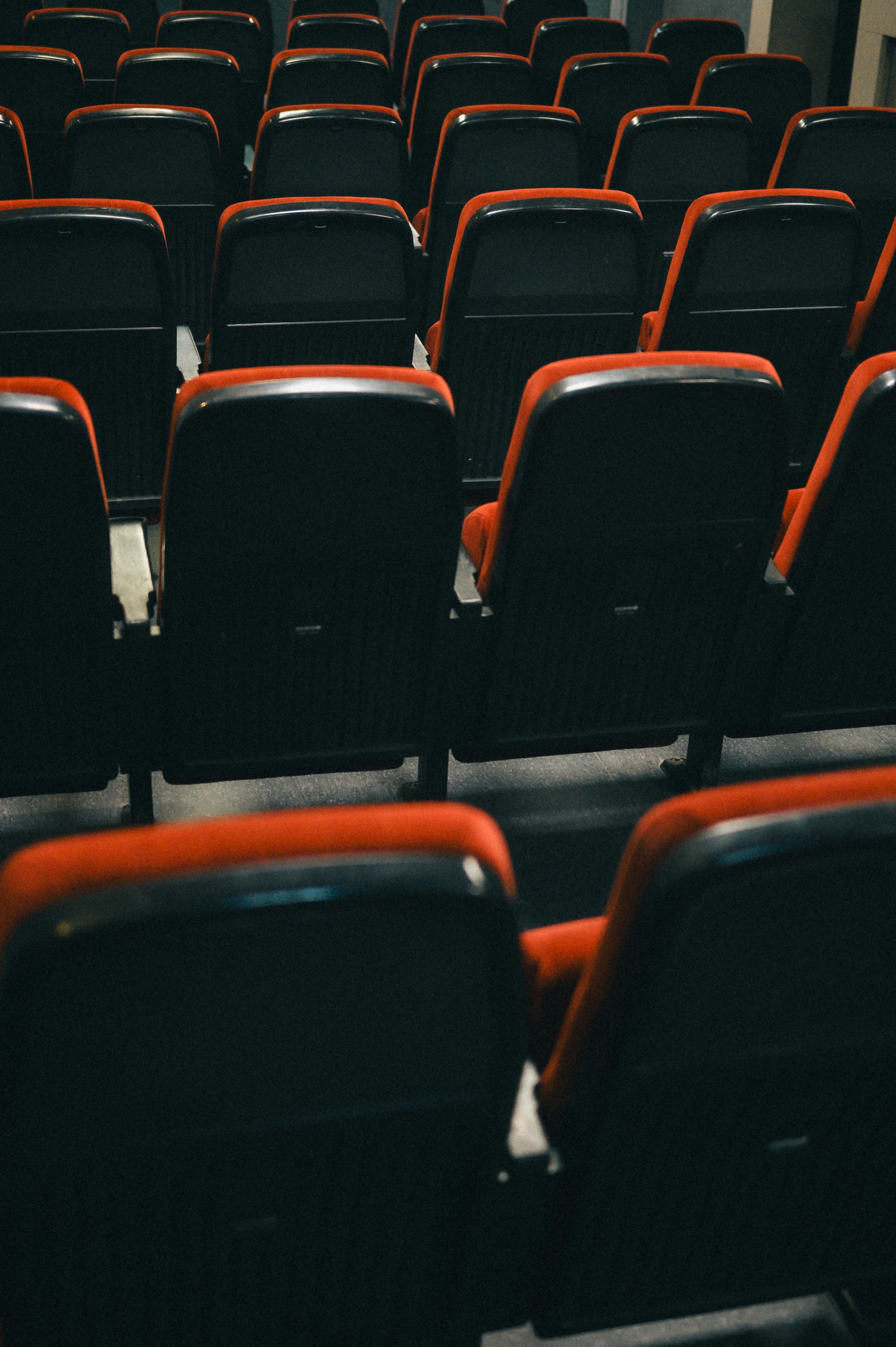 Gratis Deretan kursi teater kosong dengan desain merah dan hitam, menangkap esensi antisipasi dalam suasana dalam ruangan. Foto Stok