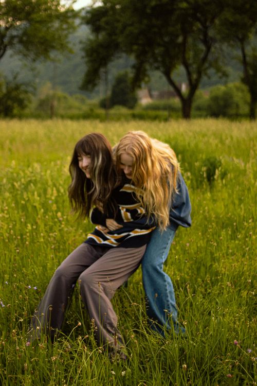 Free Two friends playing in a lush green meadow, sharing a moment of laughter. Stock Photo