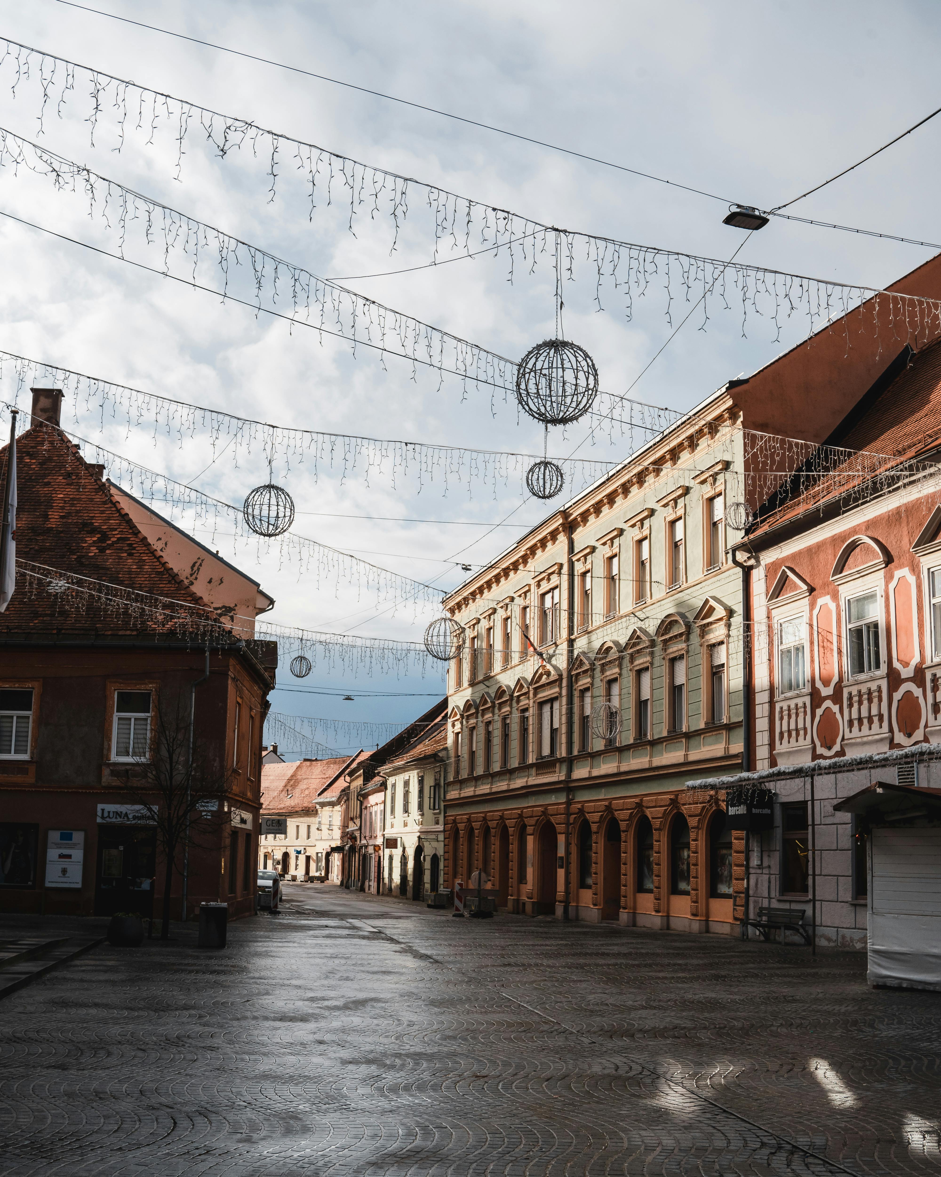 A quaint European street adorned with festive lights and decorations under a clear winter sky.