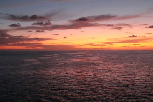 Capture the serene beauty of a vibrant sunset over the open ocean, perfect for travel inspiration.