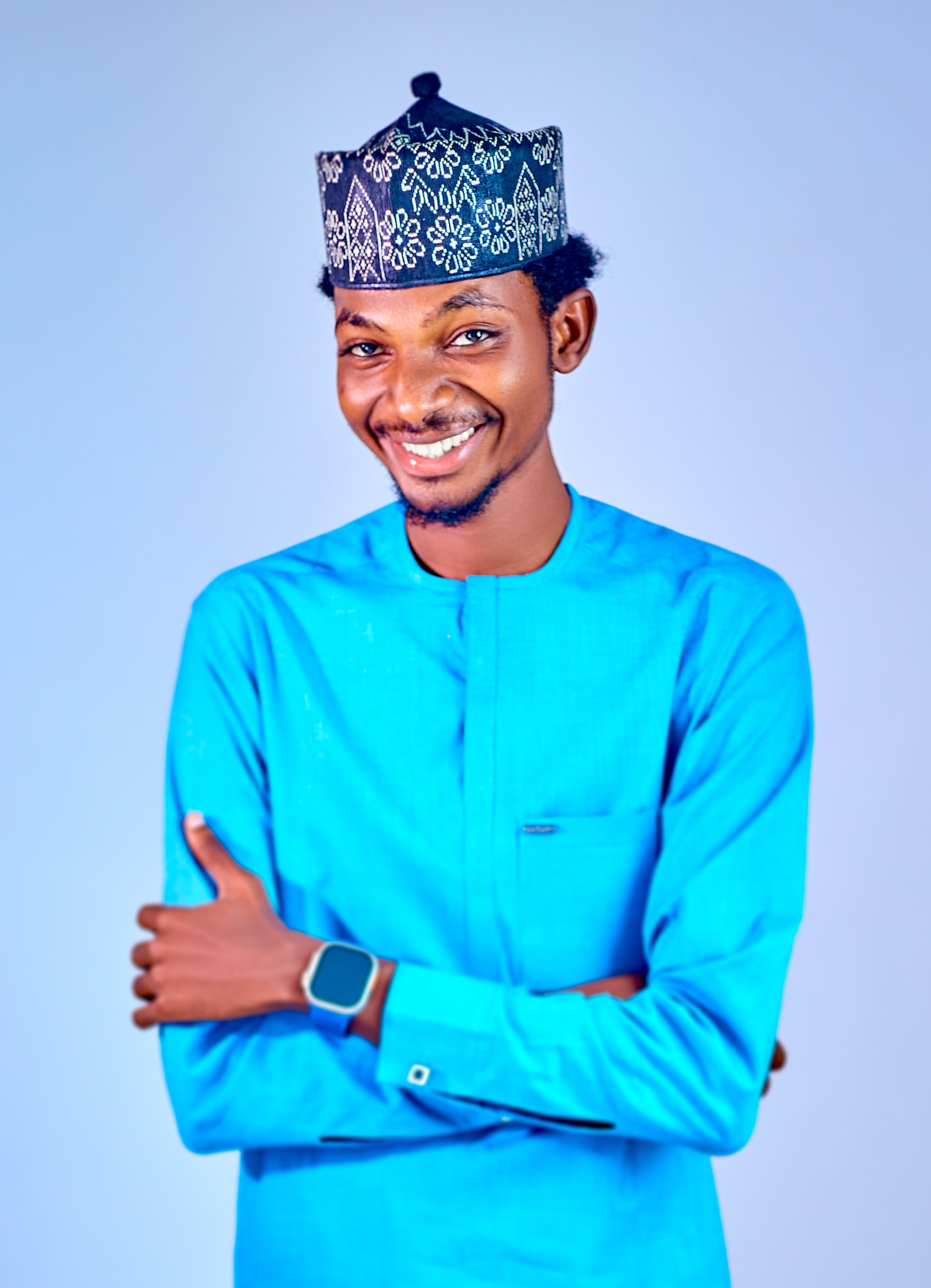 Smiling man wearing a traditional hat and bright blue outfit, posing confidently.