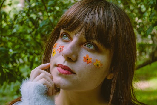 户外，一名女子脸部涂有花卉图案的特写镜头，展现了其深思的表情与自然的环境