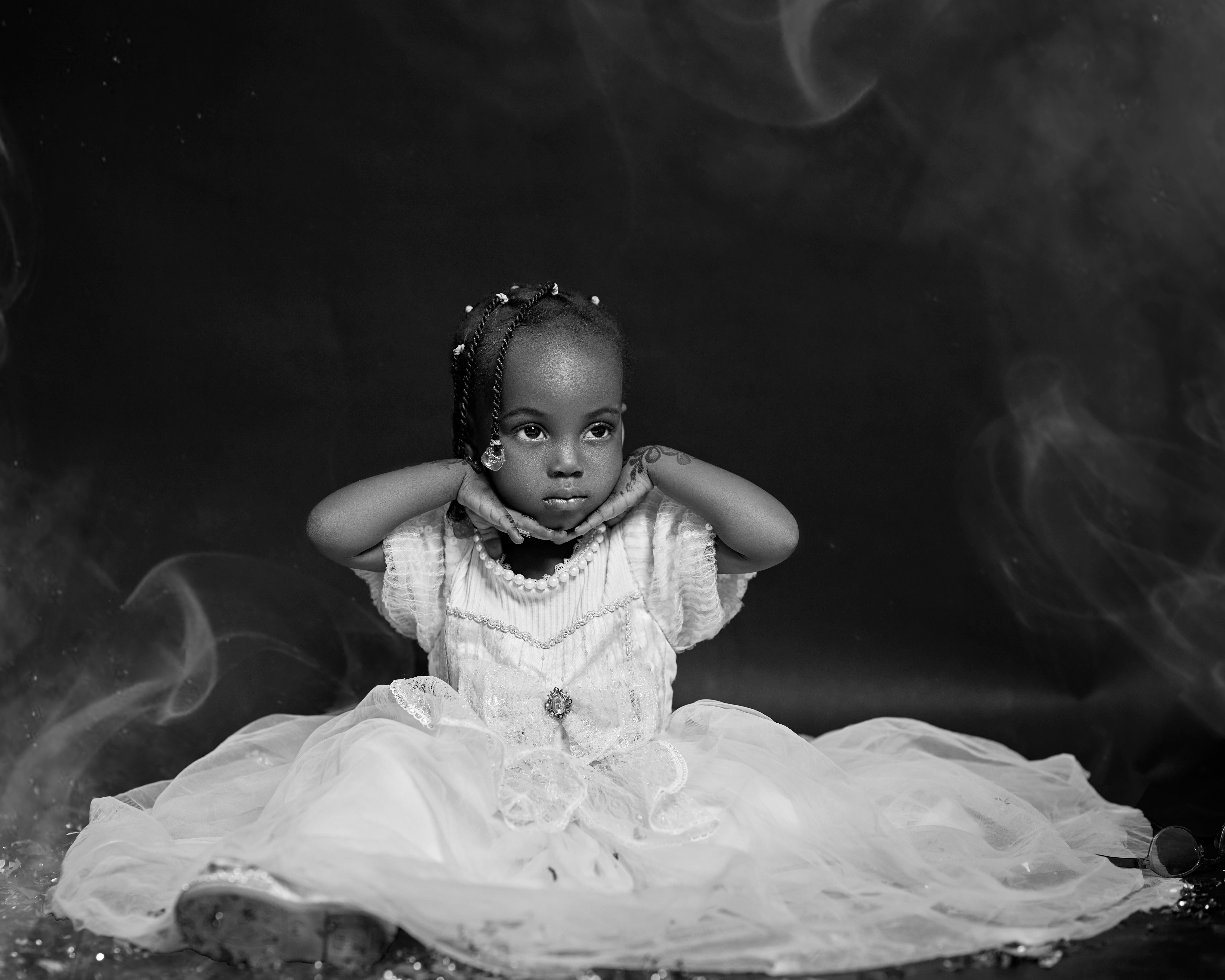 Black and white portrait of a young girl in an elegant dress, sitting gracefully.