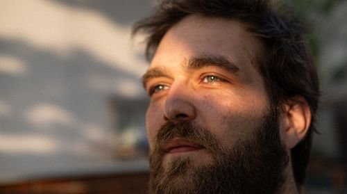 Free Close-up portrait of a man basking in sunlight, creating a warm and introspective mood. Stock Photo