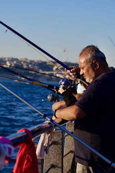 Two men enjoy fishing by the sea at sunset, capturing a serene outdoor moment.