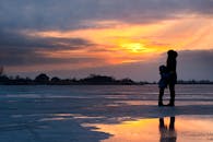 在乌克兰赫尔松结冰的湖面上，一个家庭的剪影映衬着宁静的日落