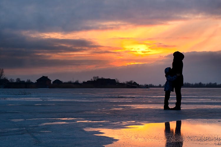 Child And Woman Standing Near Water