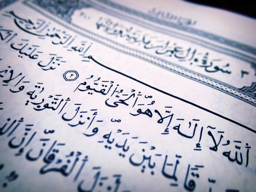 Detailed close-up of Arabic script from a Quran page, highlighting religious text and calligraphy.