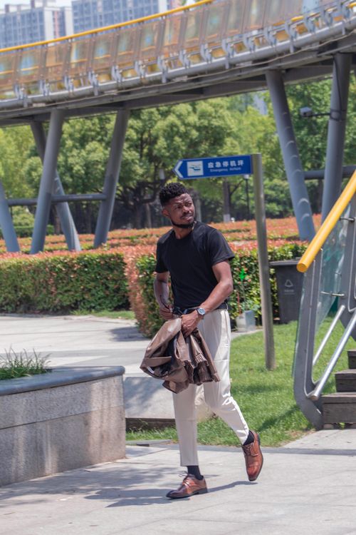 Free Man in casual attire walking through a city park on a sunny day. Stock Photo