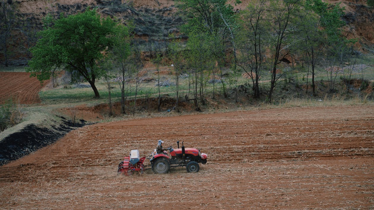 Land for sale in Kenya,7 Ultimate Guide to Avoid Scams 3 Tractor Plowing Field in Rural Landscape