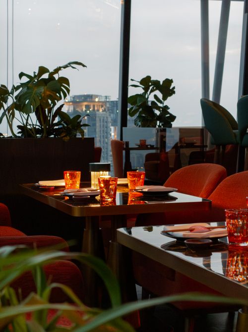 Free Sophisticated dining ambience with city views, featuring warm lighting and modern decor. Stock Photo