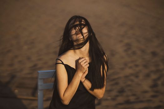 一位长发女子迎风立于沙滩，散发着优雅与情感