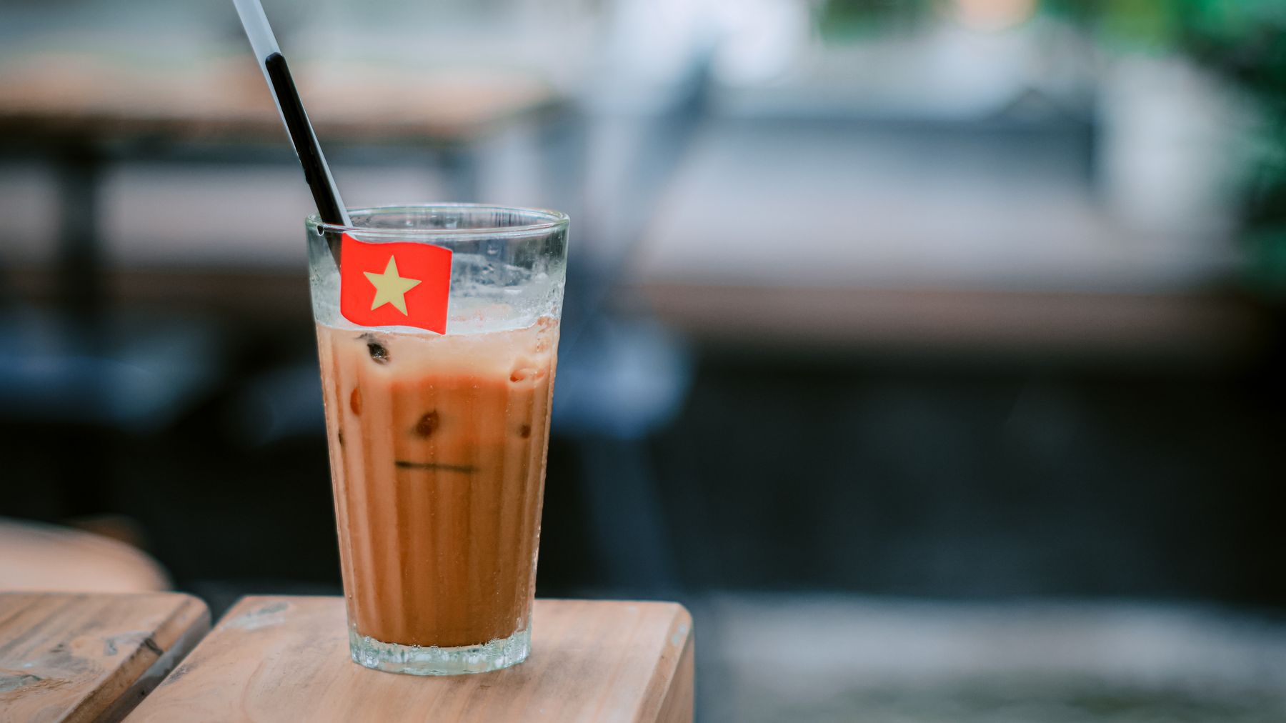 Erfrischendes Glas vietnamesischer Eiskaffee mit einer kleinen Flagge auf einem Tisch.