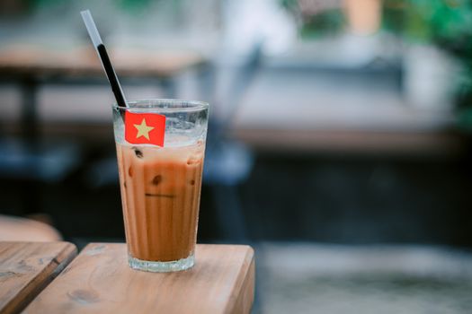 Refreshing glass of Vietnamese iced coffee with a mini flag on a table.