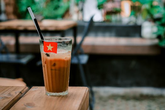 A refreshing glass of iced coffee with a straw in an outdoor café. Warm and inviting atmosphere.