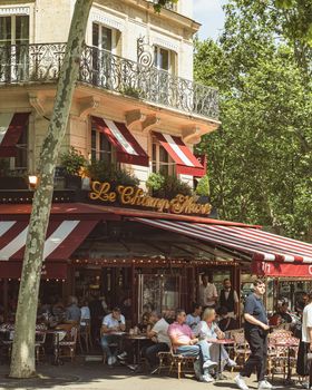 Charming street scene of Le Champs de Mars café in Paris with patrons enjoying outdoor seating.