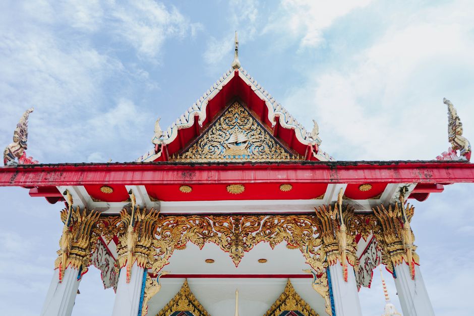 Intricate Thai temple roof against a bright sky in Bangkok, Thailand.
