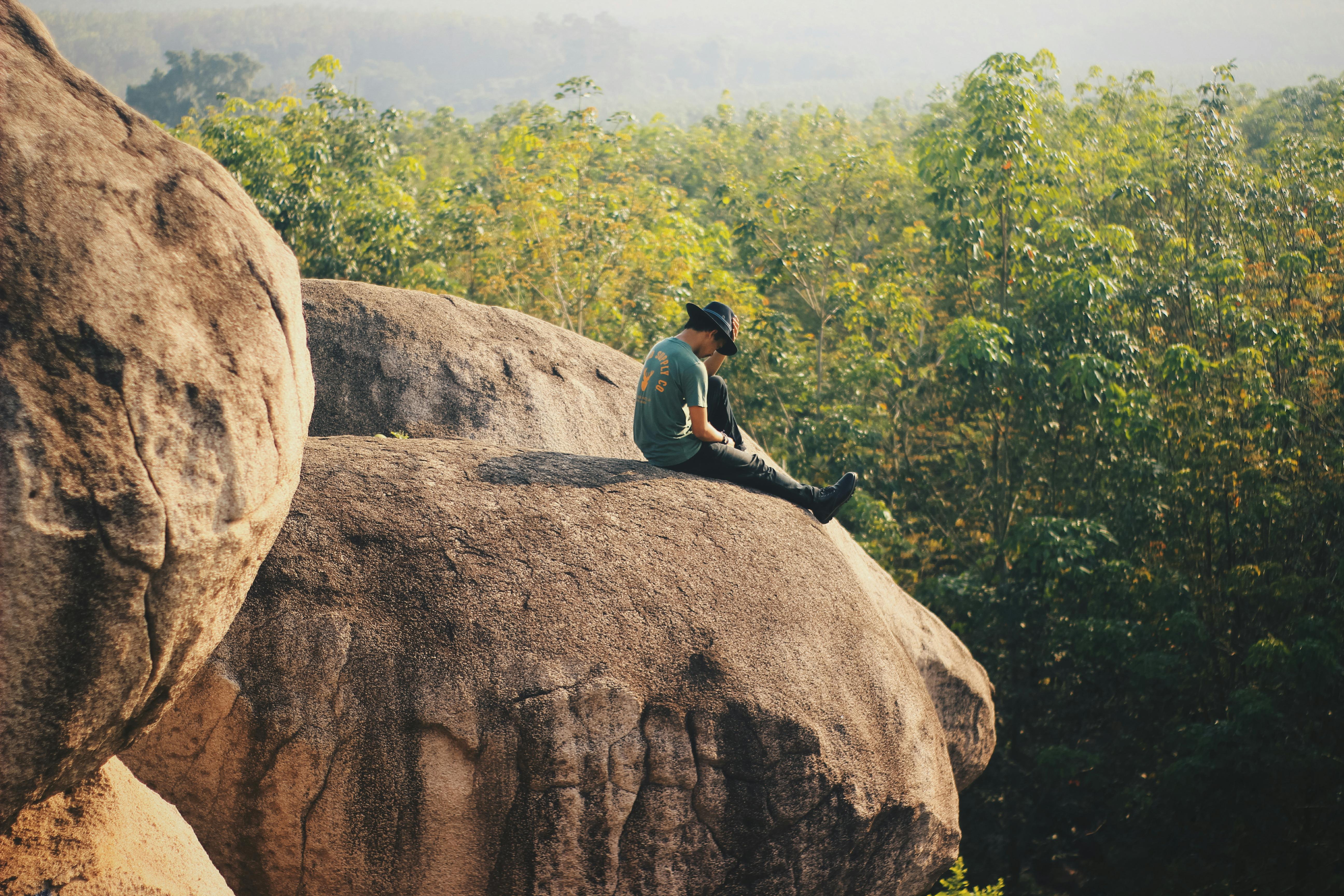 man sitting on rock cliff