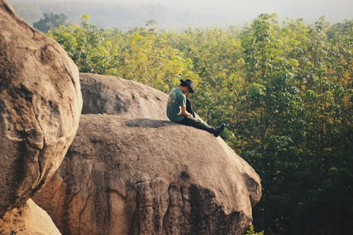 Man Sitting on Rock Cliff