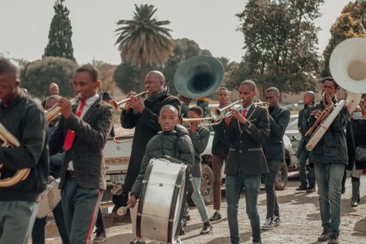 A vibrant brass band parade with musicians playing instruments on a street in Winburg, South Africa.