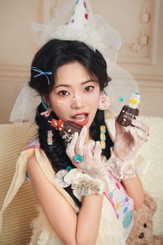 A woman in playful costume celebrates birthday holding chocolate gifts.