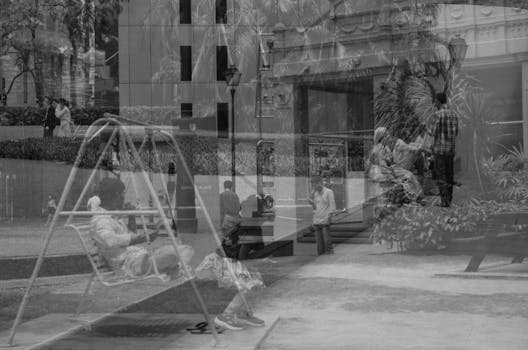 黑白双重曝光有趣地展示了城市生活和秋千上的孩子