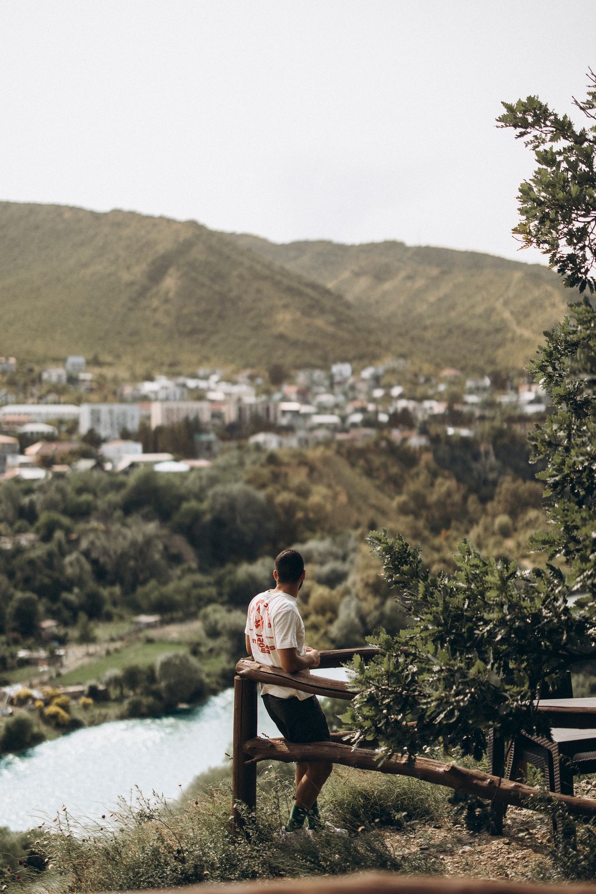 Man enjoys panoramic view of Tbilisi Georgia with lush hills and river