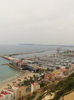 Scenic aerial view of Alicante marina and beach, bustling with visitors on a clear day.