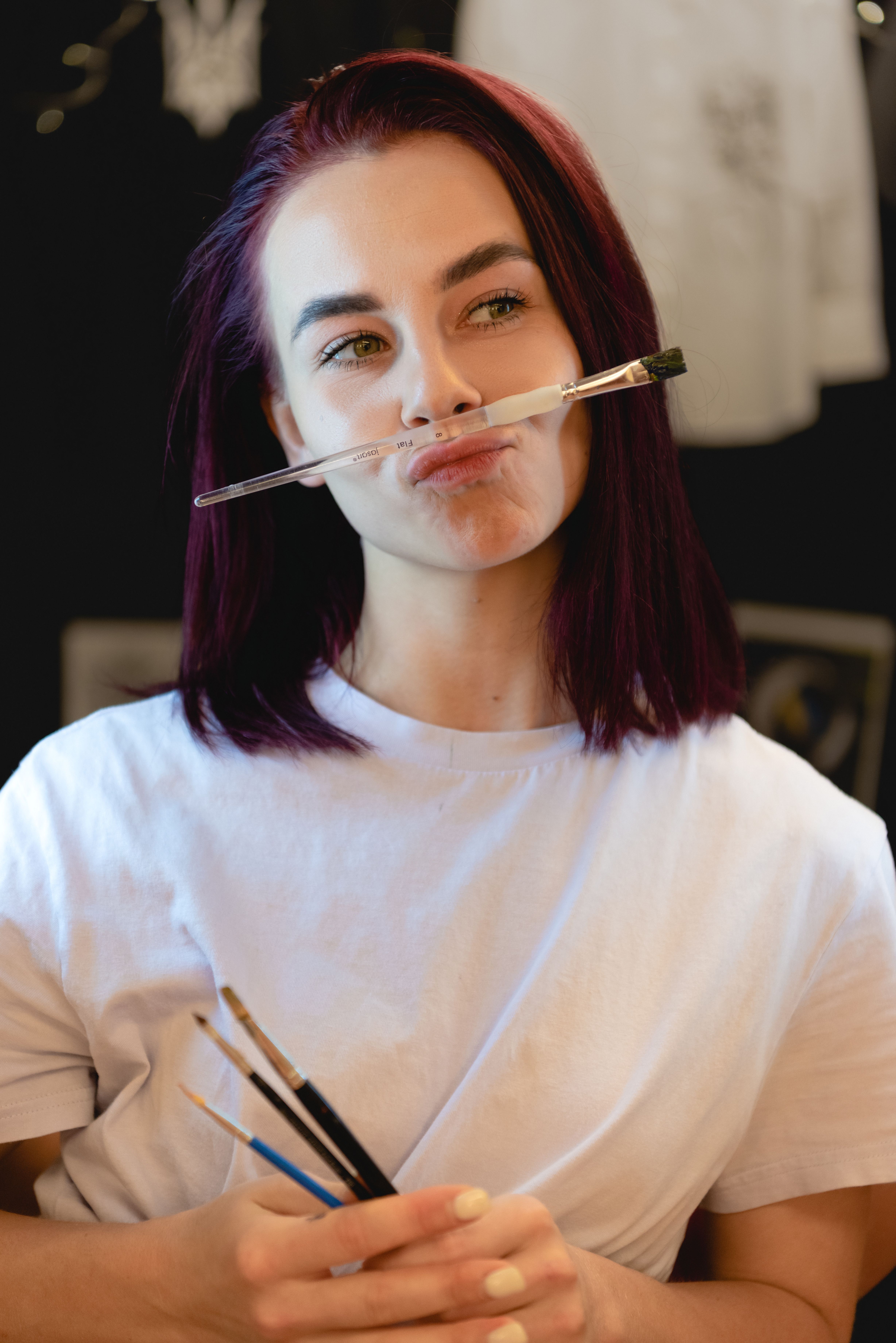 Creative young woman with paintbrushes adding a playful touch to her artistic process.