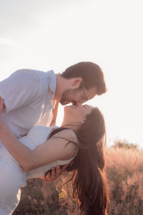 Free A couple lovingly embraces in a sunlit field, capturing a moment of romance and tenderness. Stock Photo