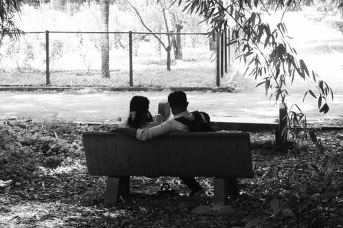 Free A father and daughter share a peaceful moment on a park bench surrounded by nature. Stock Photo