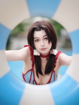 Young woman in cosplay by a pool, creatively framed through a lifebuoy.