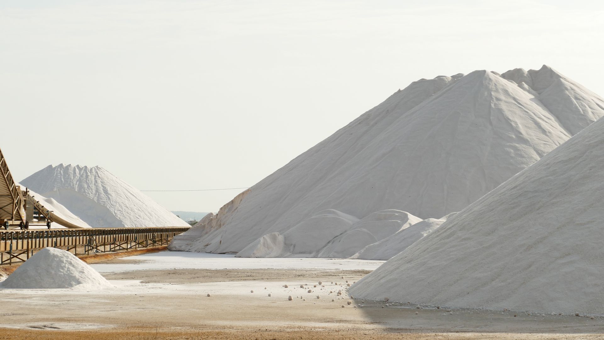 Expansive view of salt mountains and conveyor belt in a salt mine, showcasing industrial beauty.