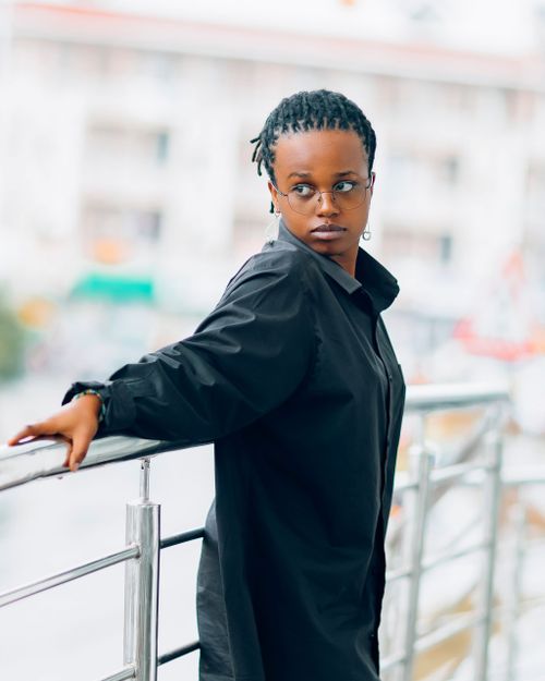 Free Confident person in black outfit posing stylishly on a city balcony. Stock Photo