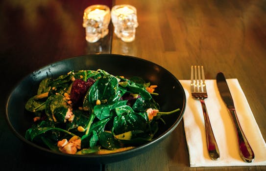 A spinach salad with beetroot and nuts served elegantly in a Sydney café setting with candlelight.