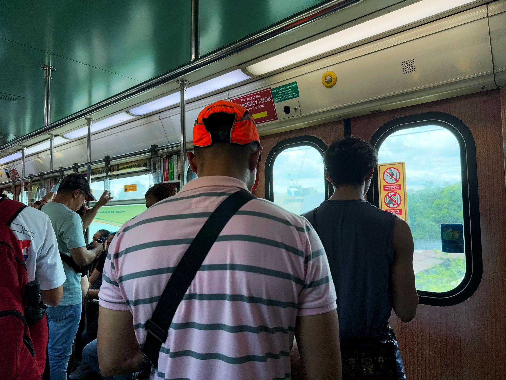 A view inside a Metro Manila train with passengers standing, capturing the urban commuter experience.