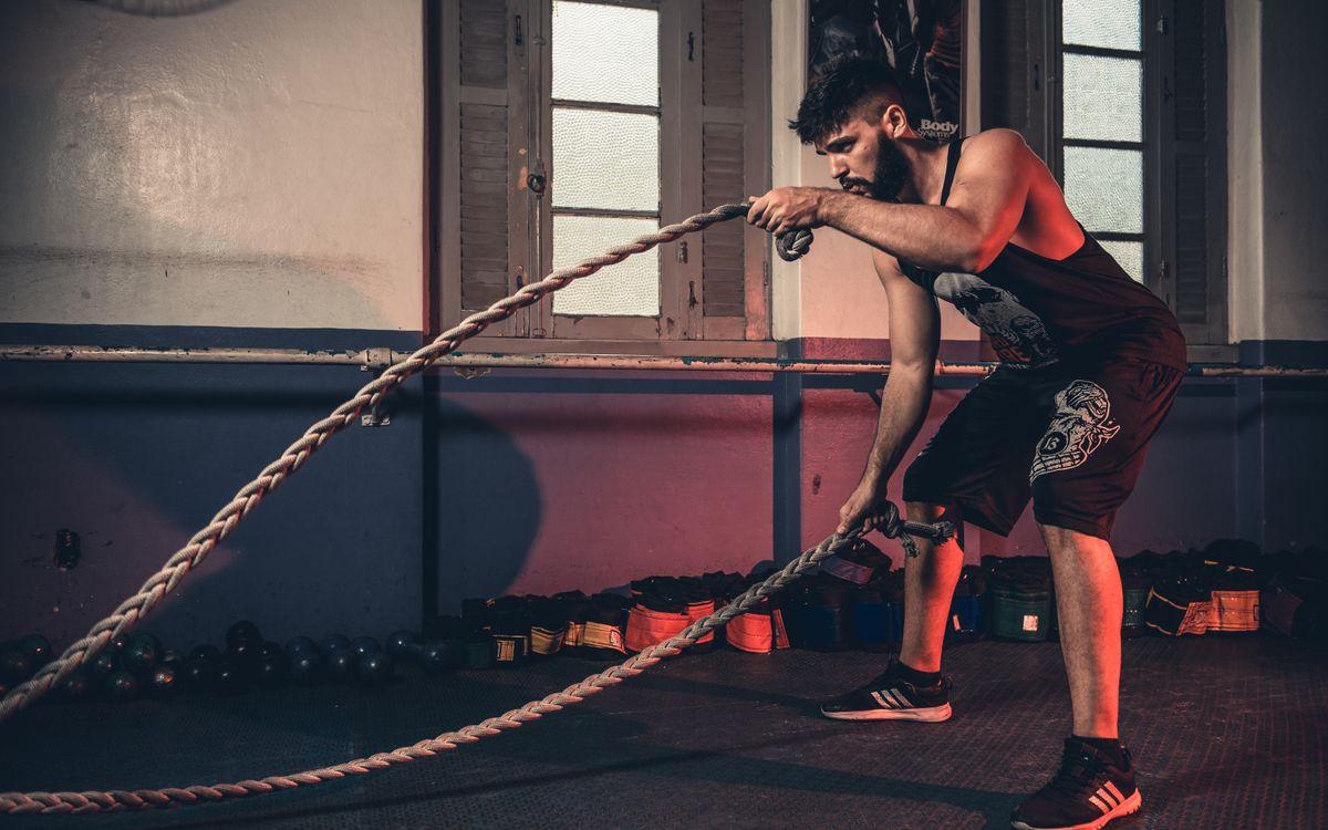 Man performing a challenging Crossfit rope exercise in an indoor gym setting.