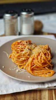 Plate of spaghetti topped with tomato sauce and grated cheese, perfect for Italian cuisine lovers.