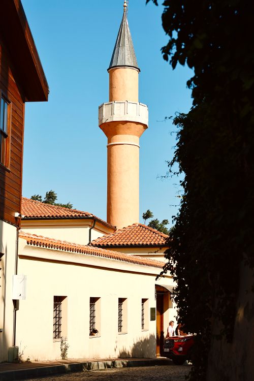 Free Sunny street view featuring a classic mosque tower under a clear blue sky. Stock Photo