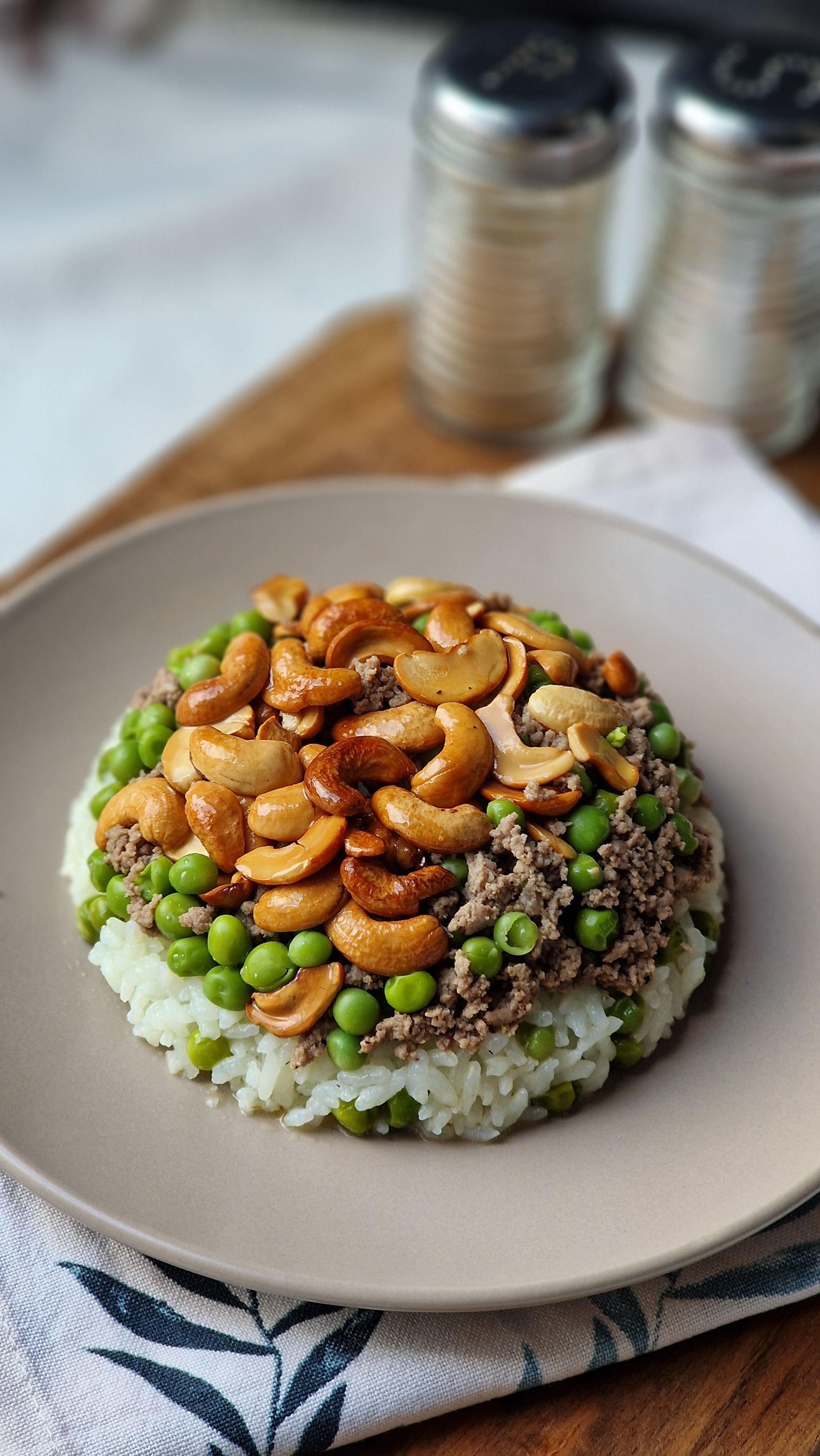 Appetizing rice plate with cashew nuts, minced meat, and green peas on a plate.