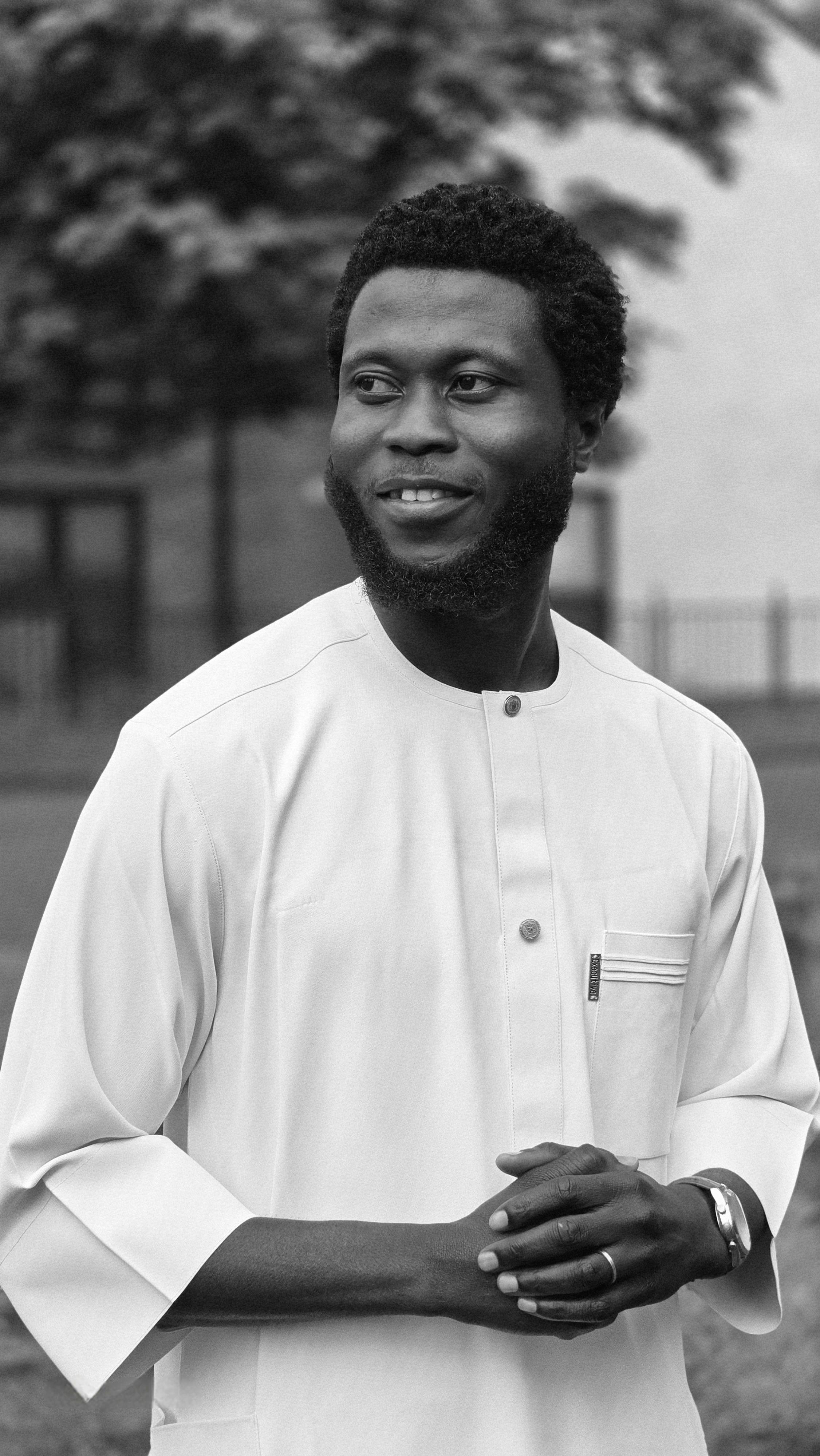 A smiling man in a traditional white kaftan poses outdoors.
