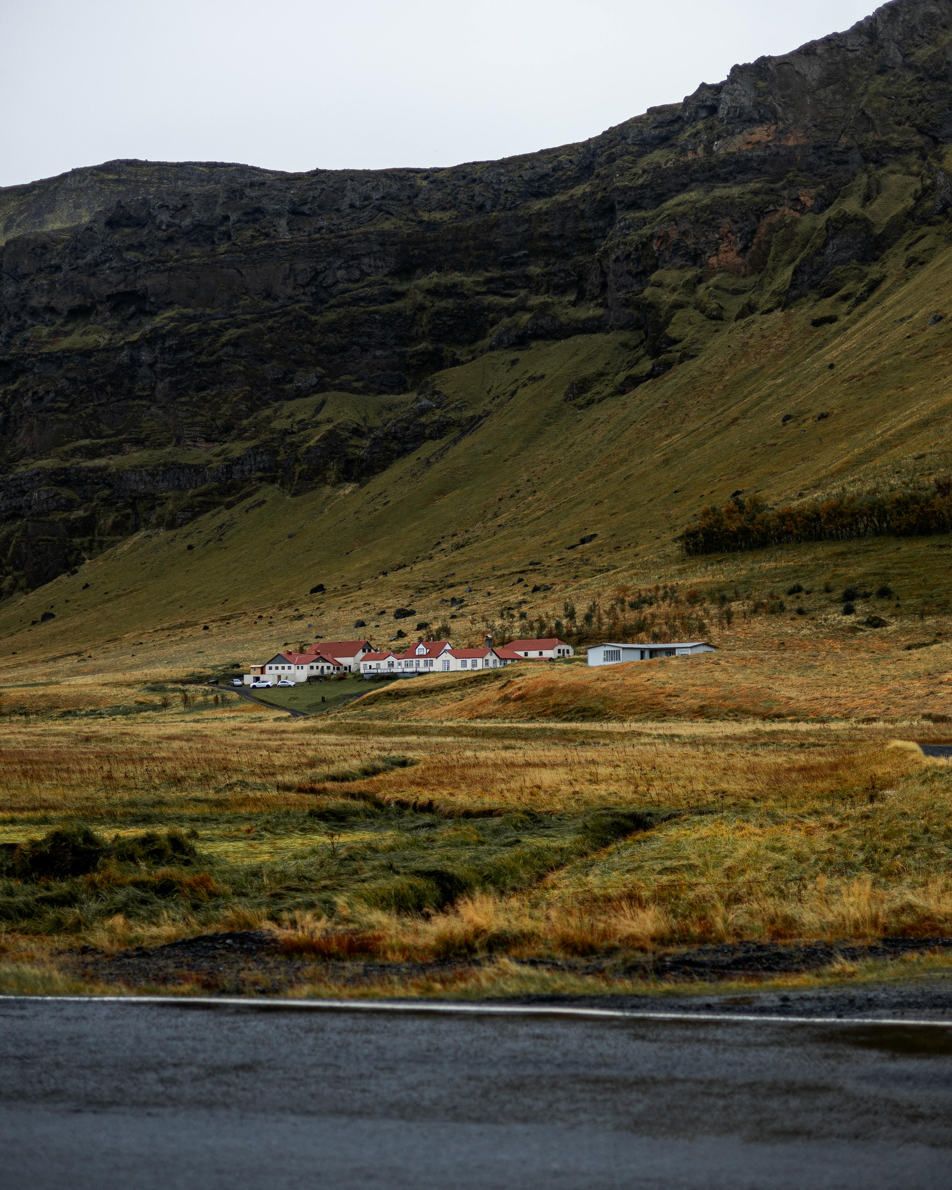 Secluded Icelandic village nestled under rugged mountain slopes, showcasing remote architecture.