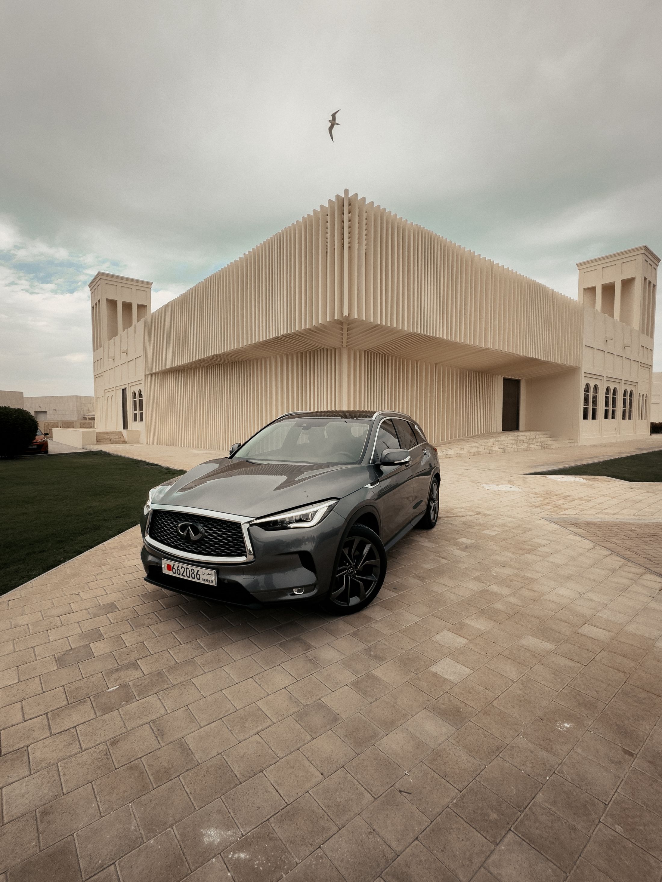 Silver vehicle photographed against modern geometric architecture
