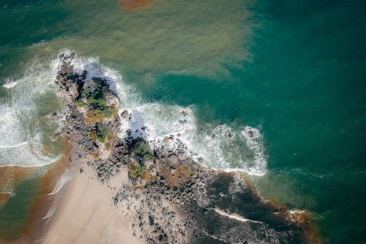 Stunning aerial capture of a rocky coastline bordered by turquoise waves and sandy shores.