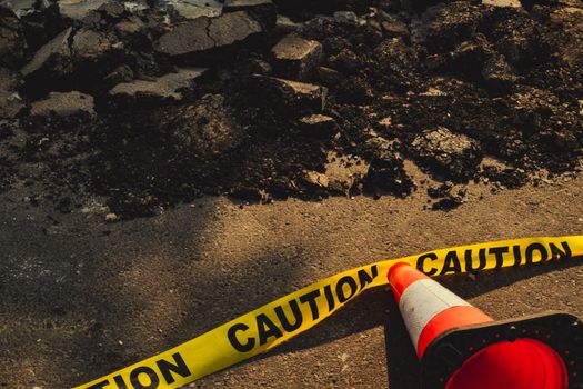 Photo by Aiden Tieulie Broken sidewalk with rubble, caution tape, and traffic cone in urban construction site.