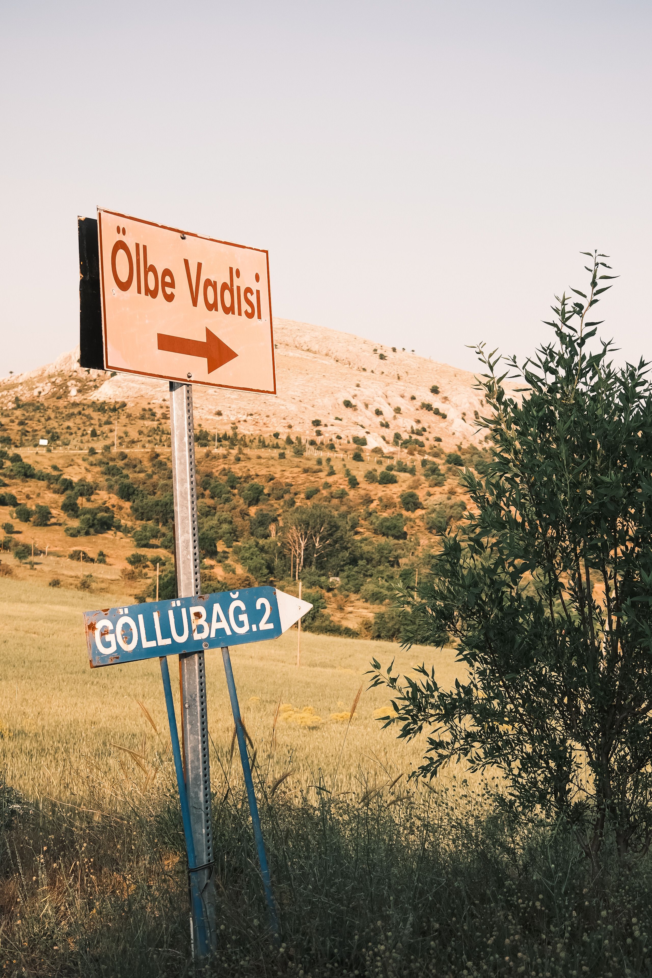 Two signs in a picturesque Turkish valley landscape during the day.