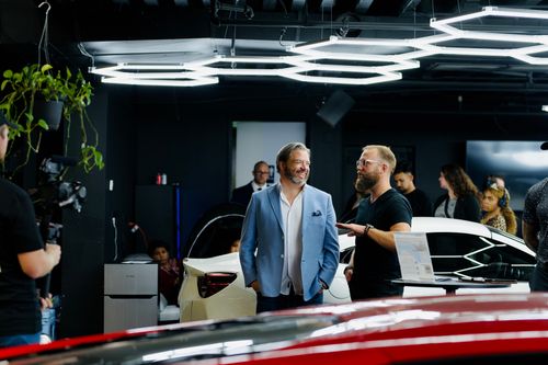 Free A luxury car event with attendees and videographers in a stylish Los Angeles showroom. Stock Photo