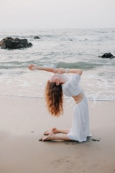 A woman gracefully performs yoga on a serene beach at sunrise, exuding tranquility.