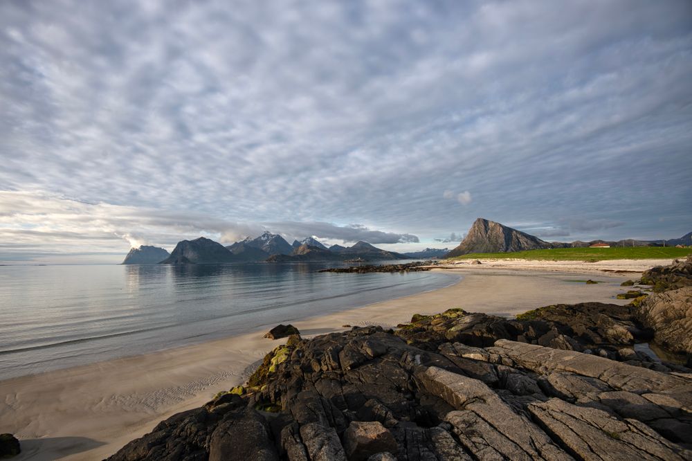 Peisaj din Lofoten cu plajă și munți sub un cer dramatic