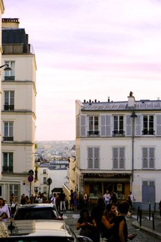 Discover Parisian charm on a bustling street during a beautiful sunset in Montmartre, Paris.